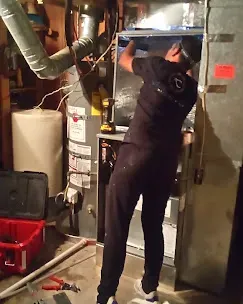 Technician inspecting a furnace for fall HVAC maintenance